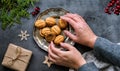 Women& x27;s elegant hands touch a plate of cookies-nuts on a dark table. Framed layout of Christmas decorations