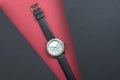 Women`s fashion wrist watch on red background. Two black sheets soar above the main background Royalty Free Stock Photo