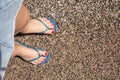 Women`s feet in the blue flip flops on a pebble beach, copy space Royalty Free Stock Photo