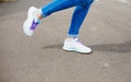 Women`s feet in blue jeans and white sneakers on the asphalt. close up Royalty Free Stock Photo