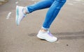 Women`s feet in blue jeans and white sneakers on the asphalt. close up Royalty Free Stock Photo