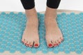 girl standing on applicators doing foot massage on a massage Mat