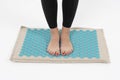 girl standing on applicators doing foot massage on a massage Mat