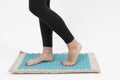 girl standing on applicators doing foot massage on a massage Mat