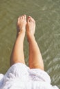Women`s feet over water Royalty Free Stock Photo