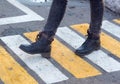 Women`s feet on a pedestrian crossing. Shoes, boots, go, walk. Asphalt, markings, mud, puddles. Autumn, slush, spring. Close up. Royalty Free Stock Photo