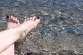 Women`s feet on sea pebbles near the water on the shore. Vacation Concept. Tanning on the Beach. Woman`s Bare Feet over Sea Royalty Free Stock Photo