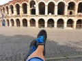 Women`s Feet In Sneakers And Famous Arena In Verona
