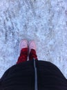 Women`s feet in sneakers on a path covered with snow