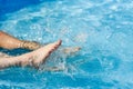 Women`s feet splashing in the pool, water spray