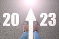 Women& x27;s feet stand on the forward arrows on the road and text on the road 2023, happy new year 2023, start of a new