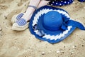 Women`s feet in striped sandals, blue hat and sunglasses on the sand Royalty Free Stock Photo