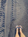 Women`s feet in white and blue sandals on the sand Royalty Free Stock Photo