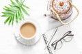 Women`s flat lay table with a cup of milk tea, teapot and clean empty notebook on a light background, top view.