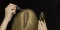 Women`s hair and hands with a cosmetic oil and a pipette. Care for the scalp, healthy hair. Black background