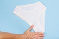 Women`s hand with beautiful panties on blue background