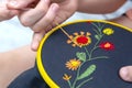 Women`s hand embroidery in a hoop, a woman embroider a pattern on dark material. Close-up. The concept of needlework, hobby,