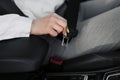 Women`s hand fastens the seat belt of the car. Close your car seat belt while sitting inside the car before driving and take a