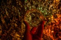 Women`s hand holding a fortune teller crystal ball and looking into the future. Blurred sparkly light background, backdrop shown