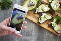 Women`s hand holding phone and taking photo of Sandwich with avo Royalty Free Stock Photo