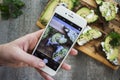 Women`s hand holding phone and taking photo of Sandwich with avo Royalty Free Stock Photo