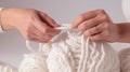 Women\'s hands BEAUTIFUL close-up, knitting for a newborn, crochet. top view on soft creamy white background.AI generated