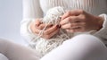 Women\'s hands BEAUTIFUL close-up, knitting for a newborn, crochet. top view on soft creamy white background.AI generated