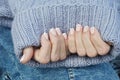 Women\'s hands with a beautiful French manicure in a warm knitted sweater. Winter trend, gel polish, shellac
