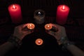 Women`s hands with bracelets and rings holding a burning candle in the dark. Royalty Free Stock Photo