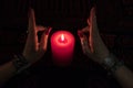 Women`s hands with bracelets and rings holding a burning candle in the dark. Royalty Free Stock Photo