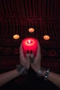 Women`s hands with bracelets and rings holding a burning candle in the dark. Royalty Free Stock Photo