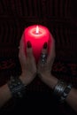 Women`s hands with bracelets and rings holding a burning candle in the dark. Royalty Free Stock Photo