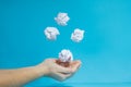 Women`s hands catch white crumpled paper balls on a blue isolated background. The concept of object levitation. Close-up,
