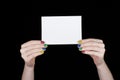 Women's hands with colored nails holding a white sheet of paper