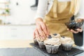 Women's hands of a confectioner, decorating cupcakes with blueberries and chocolate Royalty Free Stock Photo