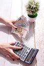 Women's hands count Russian money on a calculator, business still life with a homemade flower Royalty Free Stock Photo