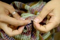 Women`s hands crochet a sweater. The color knitted sweater is torn.