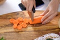 Women`s hands cut carrots with curly wavy knife on wooden Board, quilling Royalty Free Stock Photo