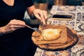 Women& x27;s hands cut khachapuri in Ajarian style with an egg on a wooden stand. Traditional Georgian pastries -