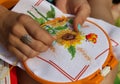 Women`s hands embroider a sunflower and a butterfly.