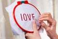 Women's hands embroider a word love