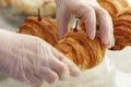 Women`s hands in gloves hold a croissant. Listing of products for sale. Business meetings and coffee breaks. Close-up Royalty Free Stock Photo