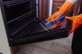 Women`s hands in gloves with a microfiber cleaning cloth clean the oven door Royalty Free Stock Photo