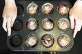 women's hands hold baked cupcake cakes in a muffin tin and eggshells isolated with shadows on a white background, high