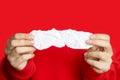 Women`s hands hold a piece of white crumpled paper on a red background. Close-up, space for text and layout, space for copying Royalty Free Stock Photo