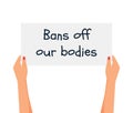 Women\'s hands hold a poster with the words Bans of our bodies.