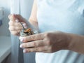 Women's hands hold a small glass jar and a spoon full of dry leaves of fragrant herbal tea. Girl impersonal photo