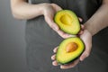 women's hands holding avocado, Caucasian woman in dark t-shirt, kitchen cooking chef Royalty Free Stock Photo