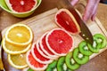 Women`s hands Housewives cut with a knife fresh grapefruit on the cutting Board of the kitchen table