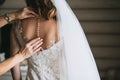 Women`s hands mother corrected dress on the back of a bride with a beautiful embroidered veil and buttons Royalty Free Stock Photo